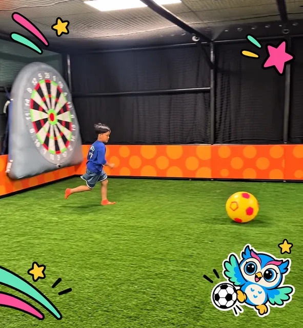 A child kicking a ball on the mini soccer field